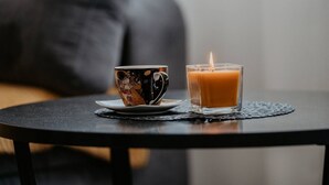 Eine Tasse und eine Kerze auf einem kleinen runden Tisch.