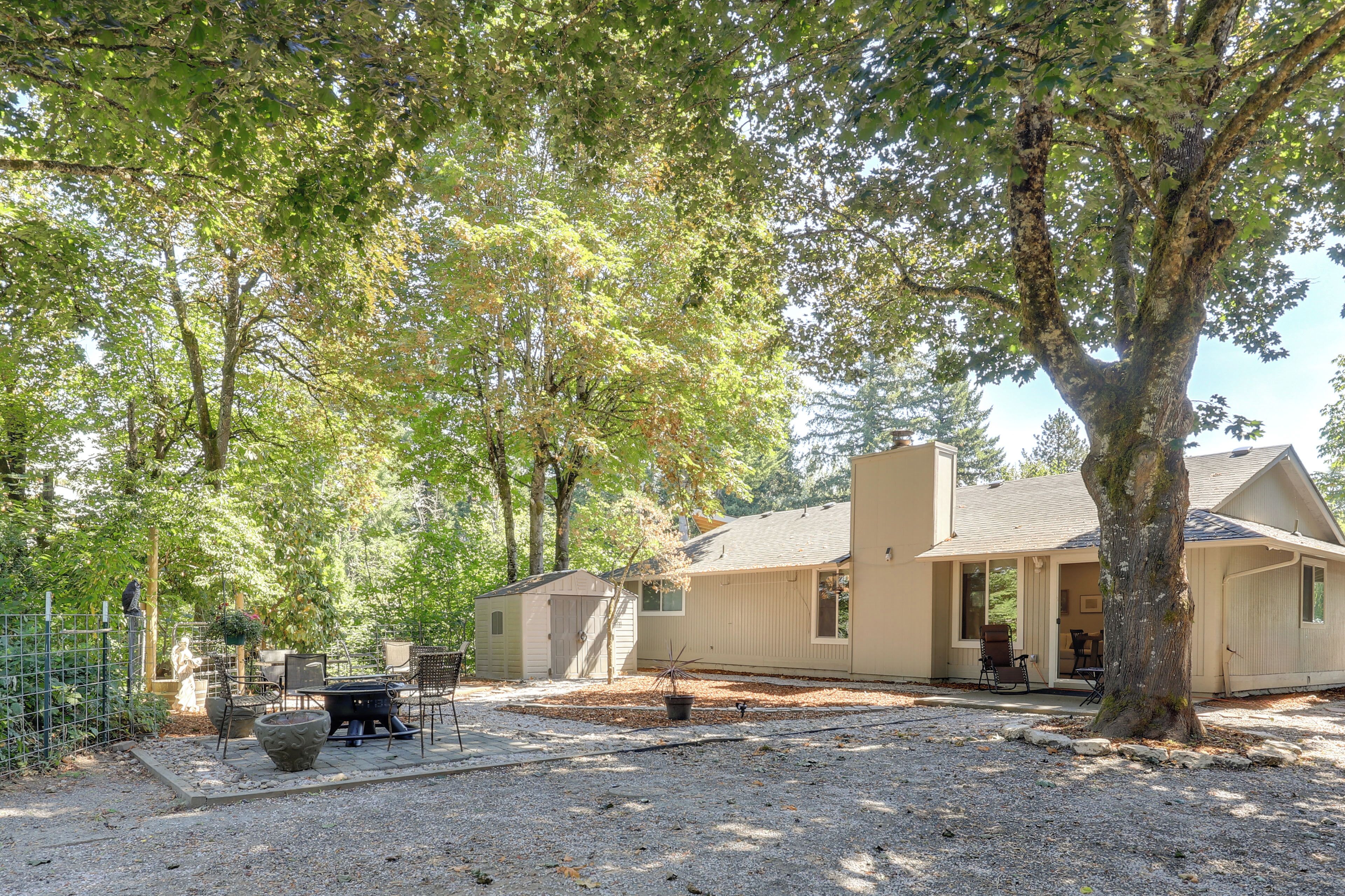 A house with a covered patio, a fire pit, and a small shed.