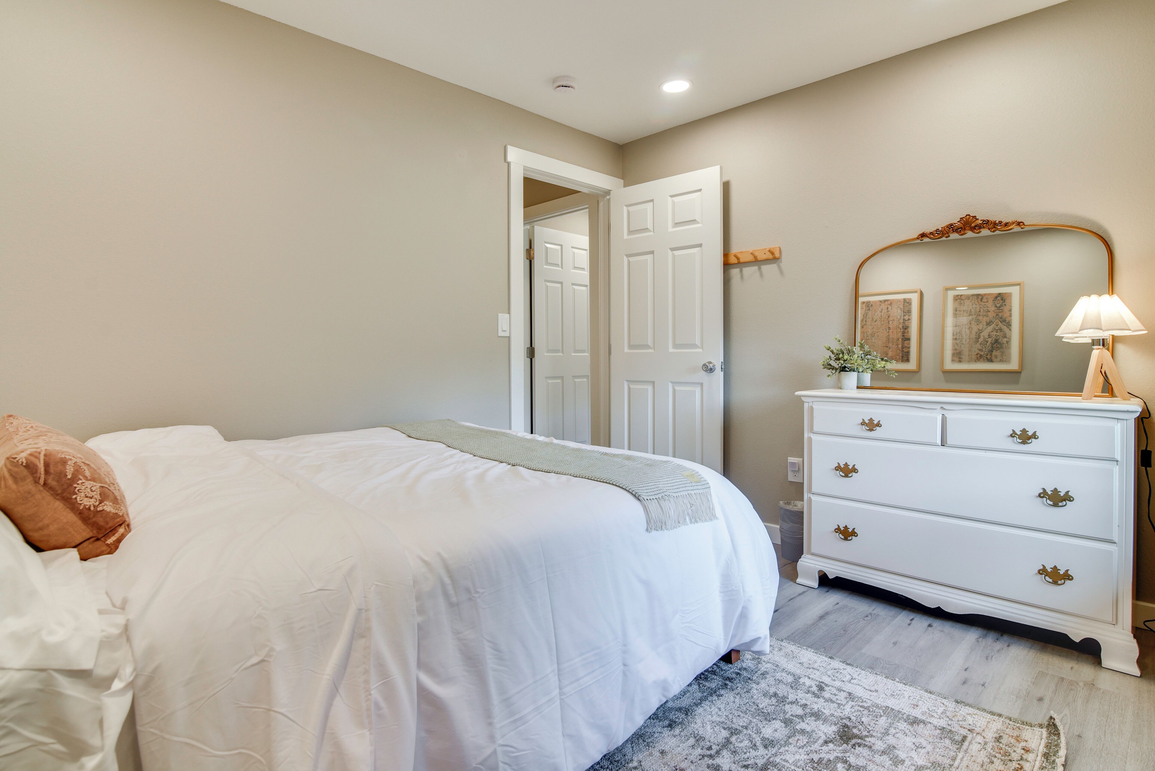 Un dormitorio con una cama, un aparador y una puerta que da a otra habitación.