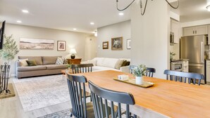 A modern living room with a sofa, dining table, and chairs. There is a kitchen area with a refrigerator and microwave. - Peace & Serenity in Gresham! Sleek Home w/ Yard (Gresham)
