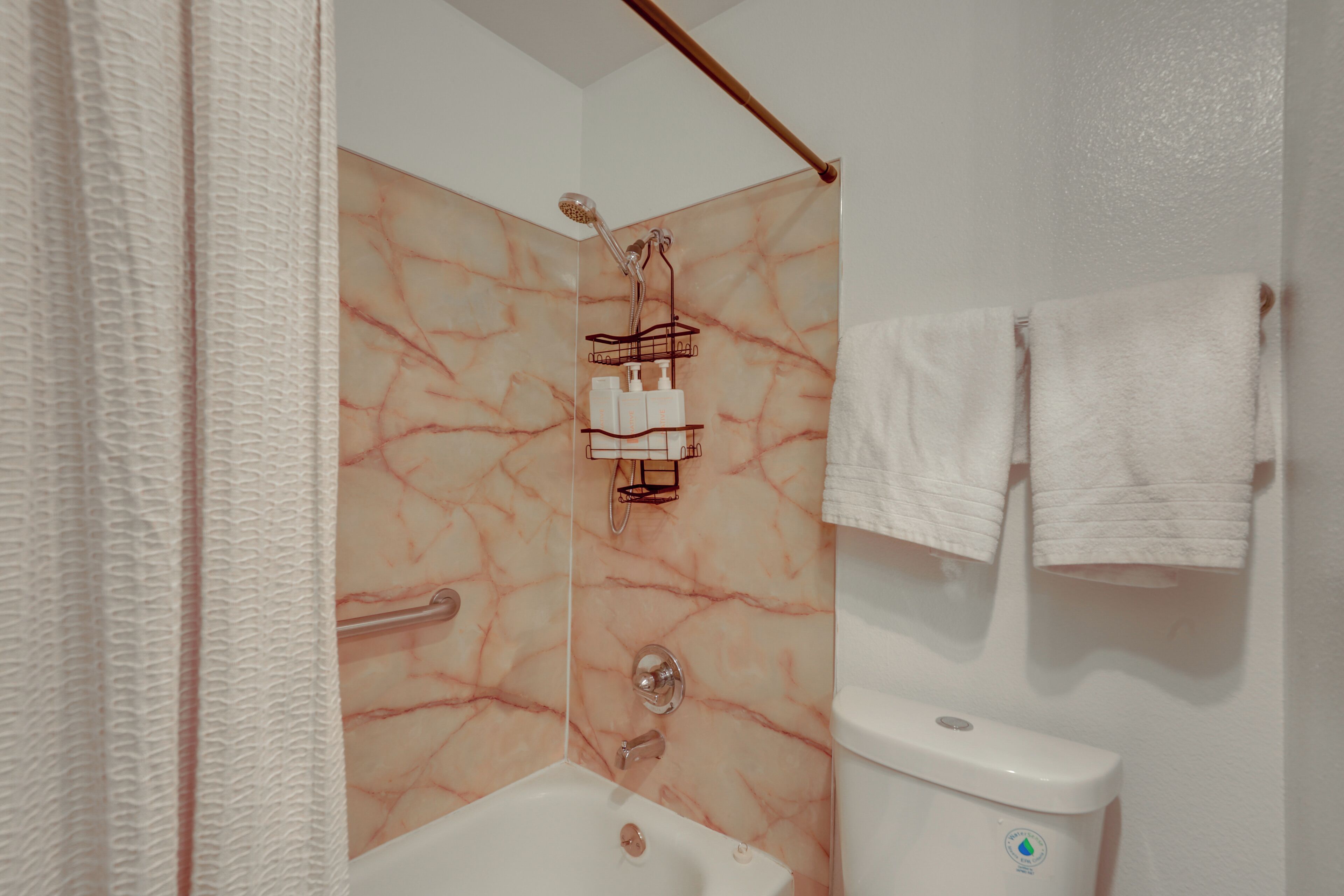 Ein Badezimmer mit Dusche, Toilette und Handtuchhalter.