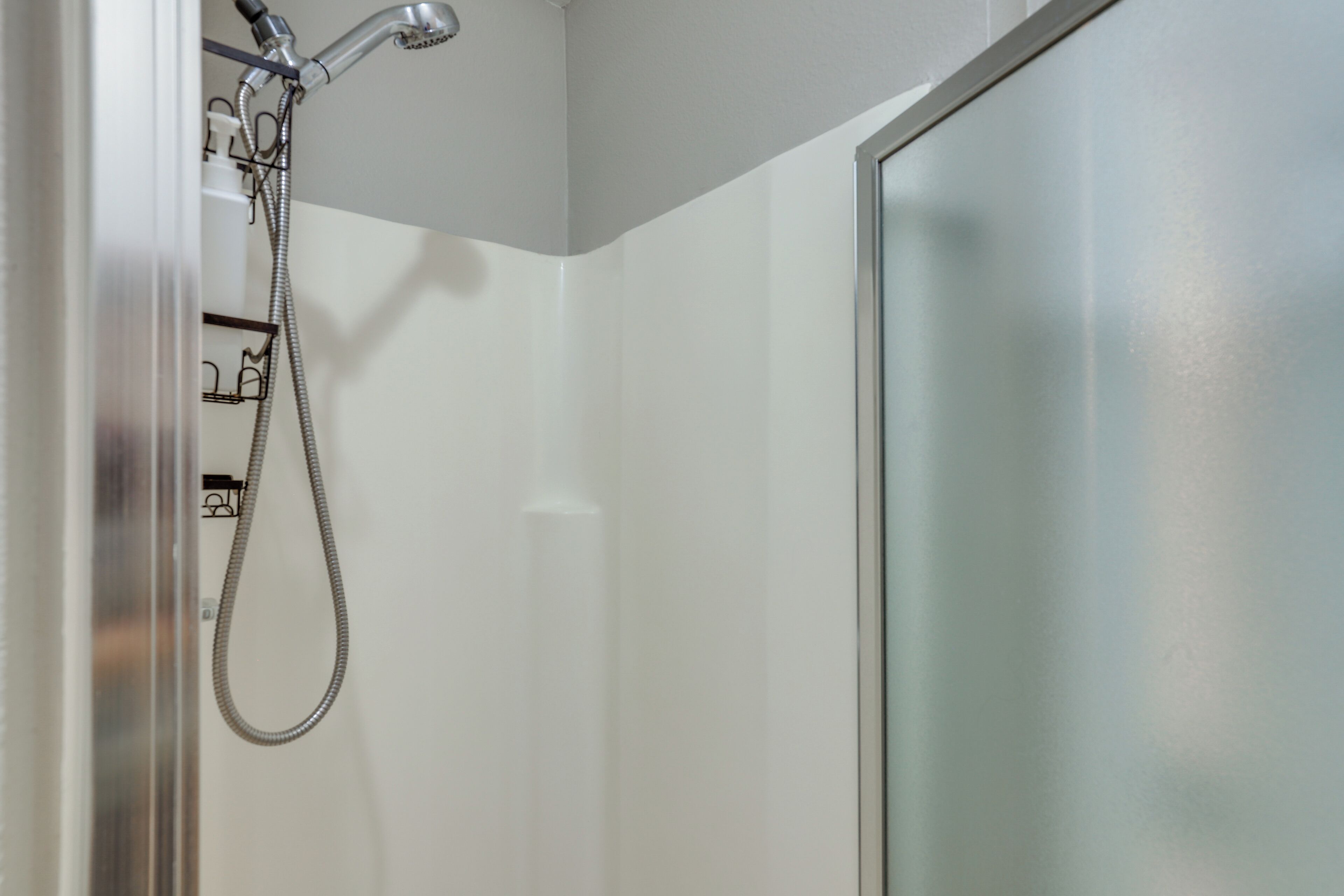 A shower with a handheld hose and a wall-mounted showerhead.
