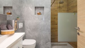 A modern bathroom with a marble wall, a wooden shower enclosure, and a white toilet. - Two Bedroom Apartment (Kaštel Sućurac)