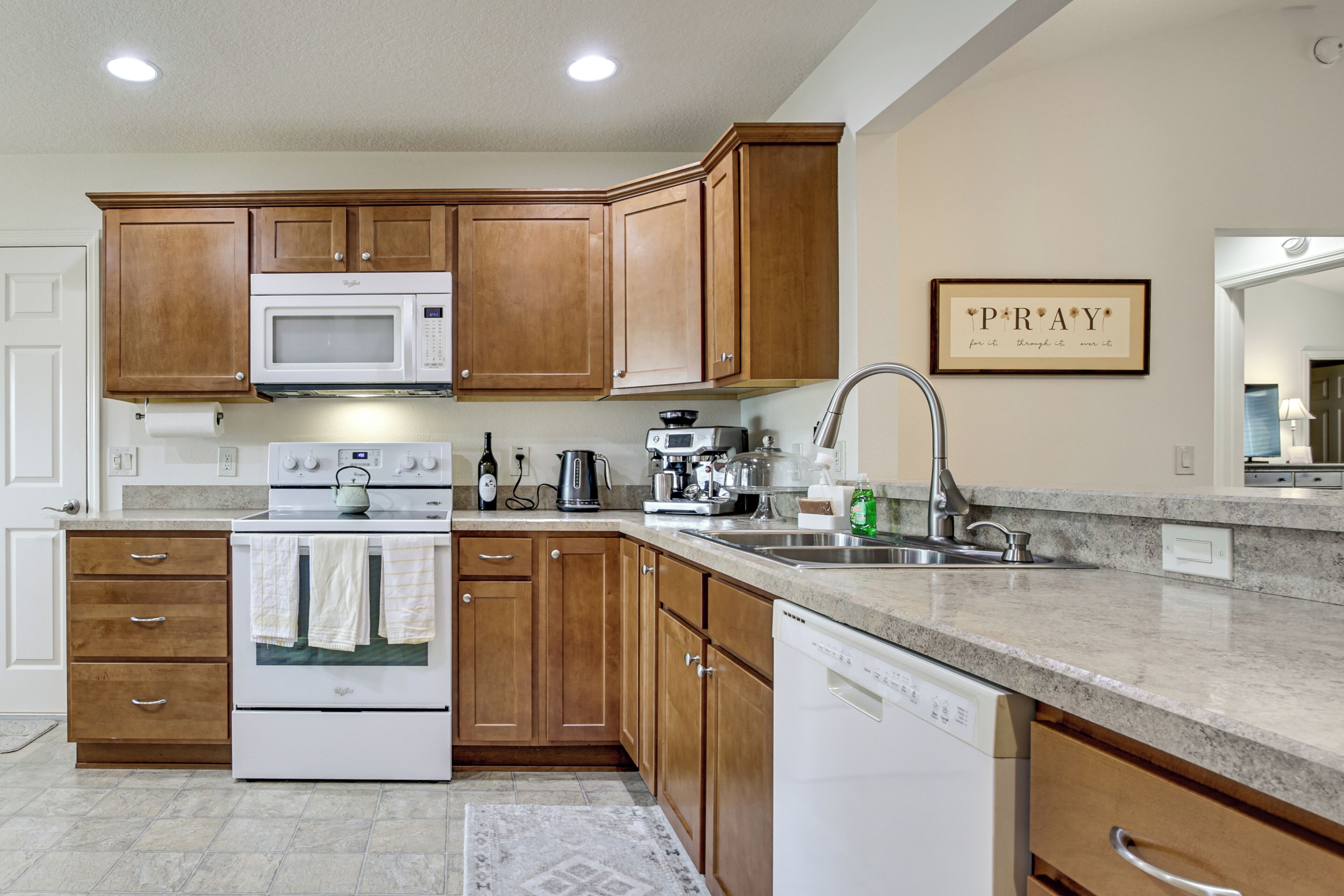 A modern kitchen with wooden cabinets, a built-in microwave, an oven, a dishwasher, and a granite countertop.