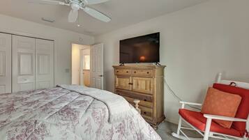 A bedroom with a bed, a dresser, a television, and a rocking chair.