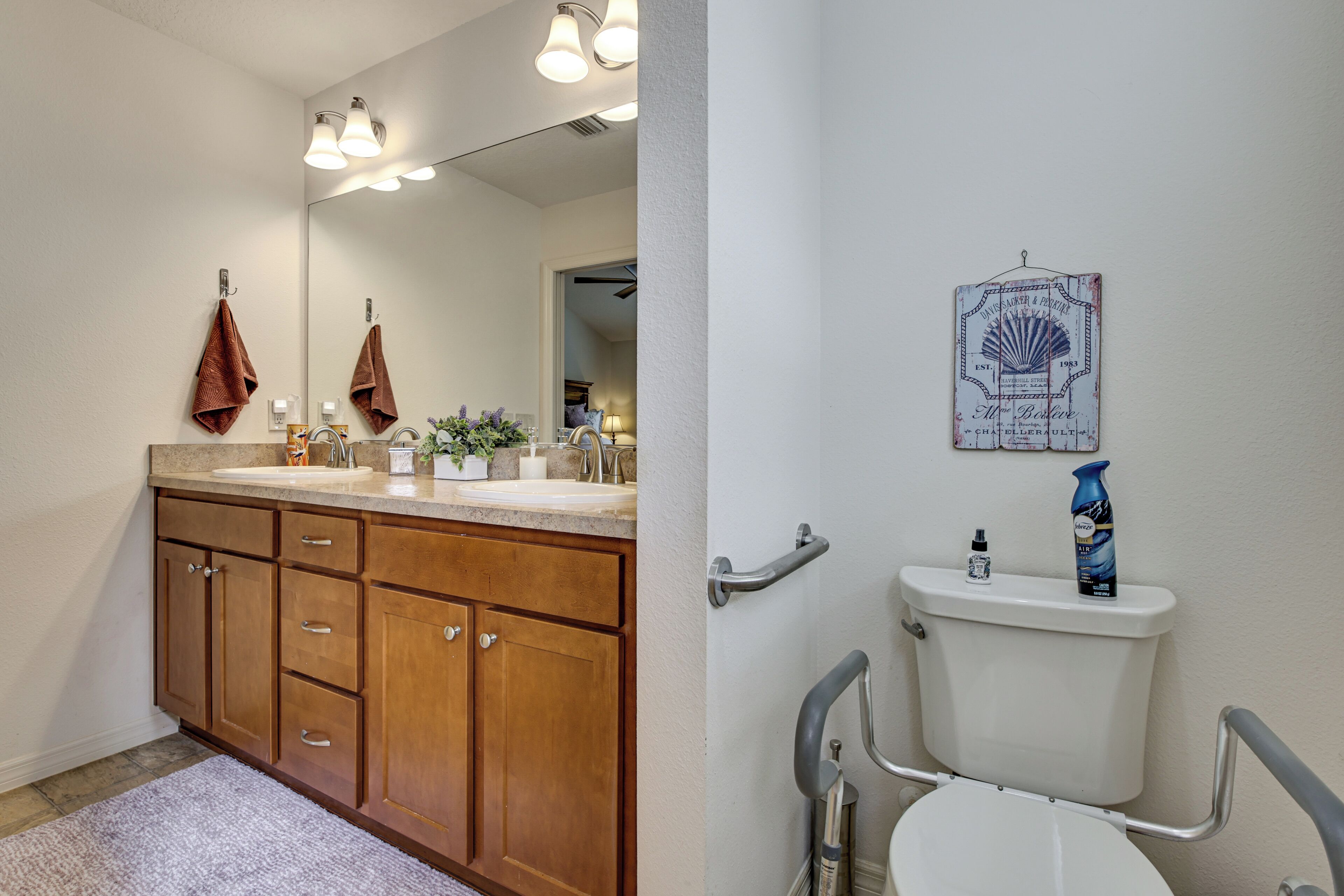 A bathroom with a wooden vanity, a sink, a mirror, and a toilet.
