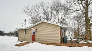 A small, single-story house with a red door and a covered porch area. - Deck & Fire Pit! Muskingum Fishing Cabin (Dresden)