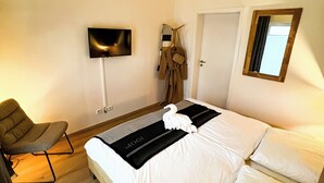 Une chambre d’hôtel avec un lit, une chaise, une télévision et une fenêtre.