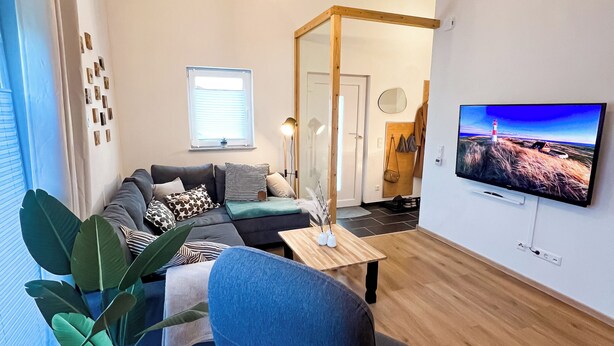 Un salon moderne avec un canapé, une table basse, un téléviseur et une grande plante.