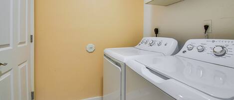 Une buanderie équipée de deux machines à laver, avec une porte blanche et un mur jaune.