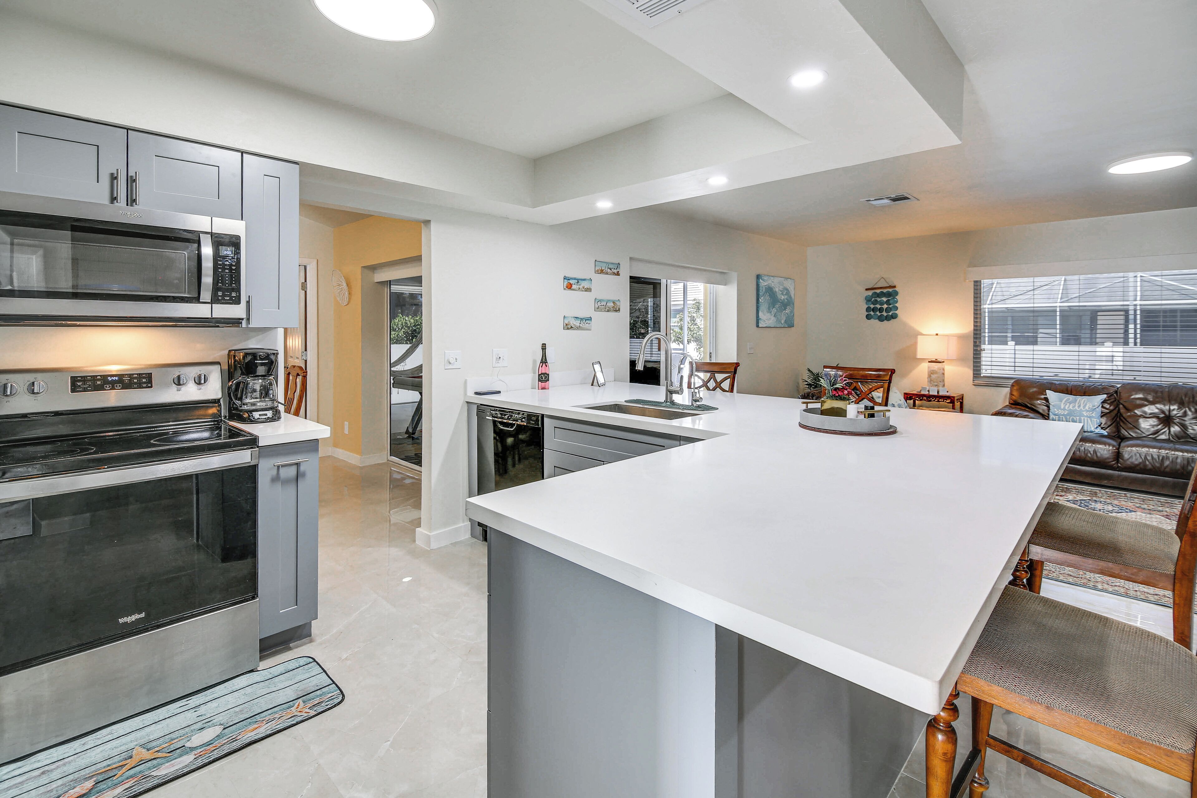 A modern kitchen with stainless steel appliances, a large island, and a dining area with a leather couch.