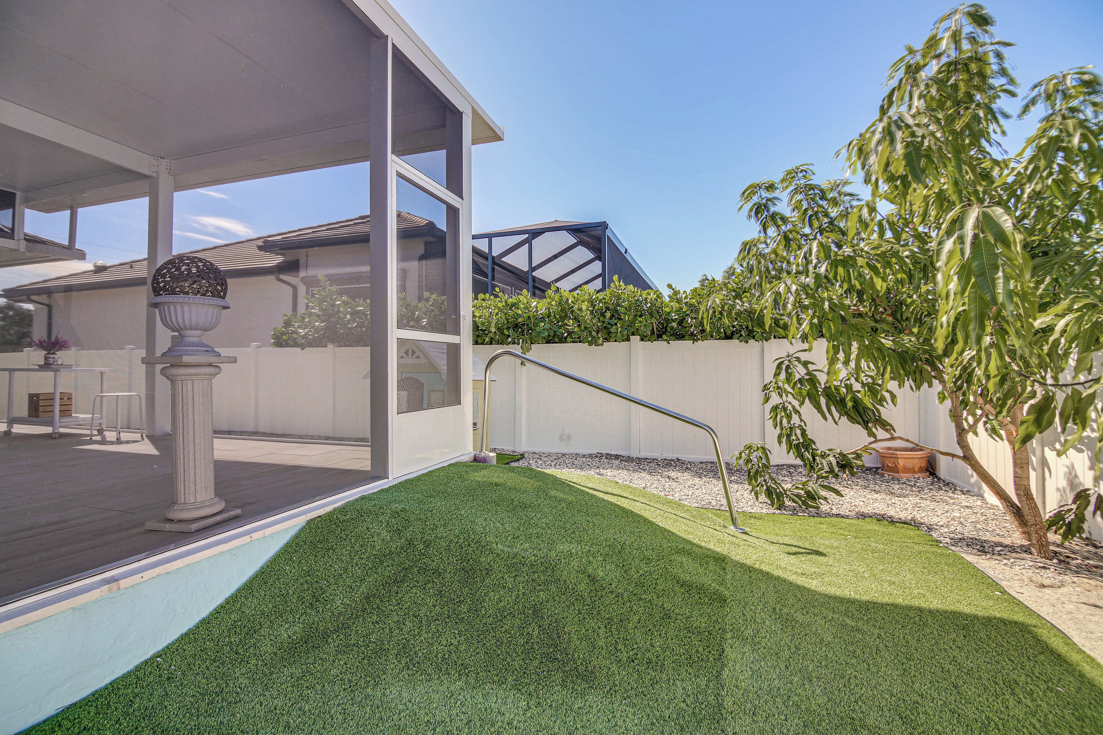 Una casa moderna con un porche cubierto, un césped cuidado y un árbol grande.