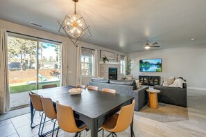 Una sala de estar moderna con comedor, chimenea y televisor grande.