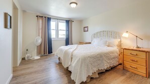 A bedroom with a bed, bedside tables, a fan, and a window with curtains.