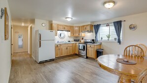 A kitchen with wooden cabinets, a refrigerator, a microwave, an oven, and a dining table with chairs.