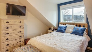 A bedroom with a bed, a dresser, a television, and a window with a view. - Work & Play in Walkable Midtown Coeur D'alene! (Coeur d'Alene)