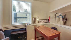 A room with a wooden table, a window with blinds, a fireplace, and a wall-mounted coat rack. - Work & Play in Walkable Midtown Coeur D'alene! (Coeur d'Alene)