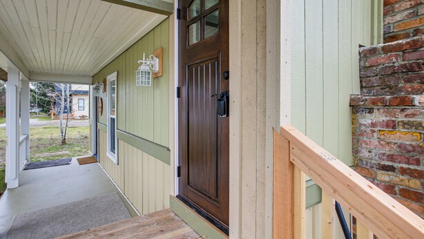 A wooden front porch with a brown door, a brick wall, and a green door frame. - Work & Play in Walkable Midtown Coeur D'alene! (Coeur d'Alene)