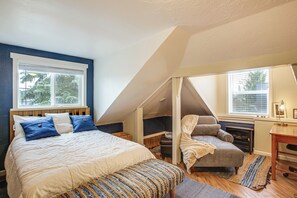 A bedroom with a large bed, a chair, a desk, and a window. - Work & Play in Walkable Midtown Coeur D'alene! (Coeur d'Alene)