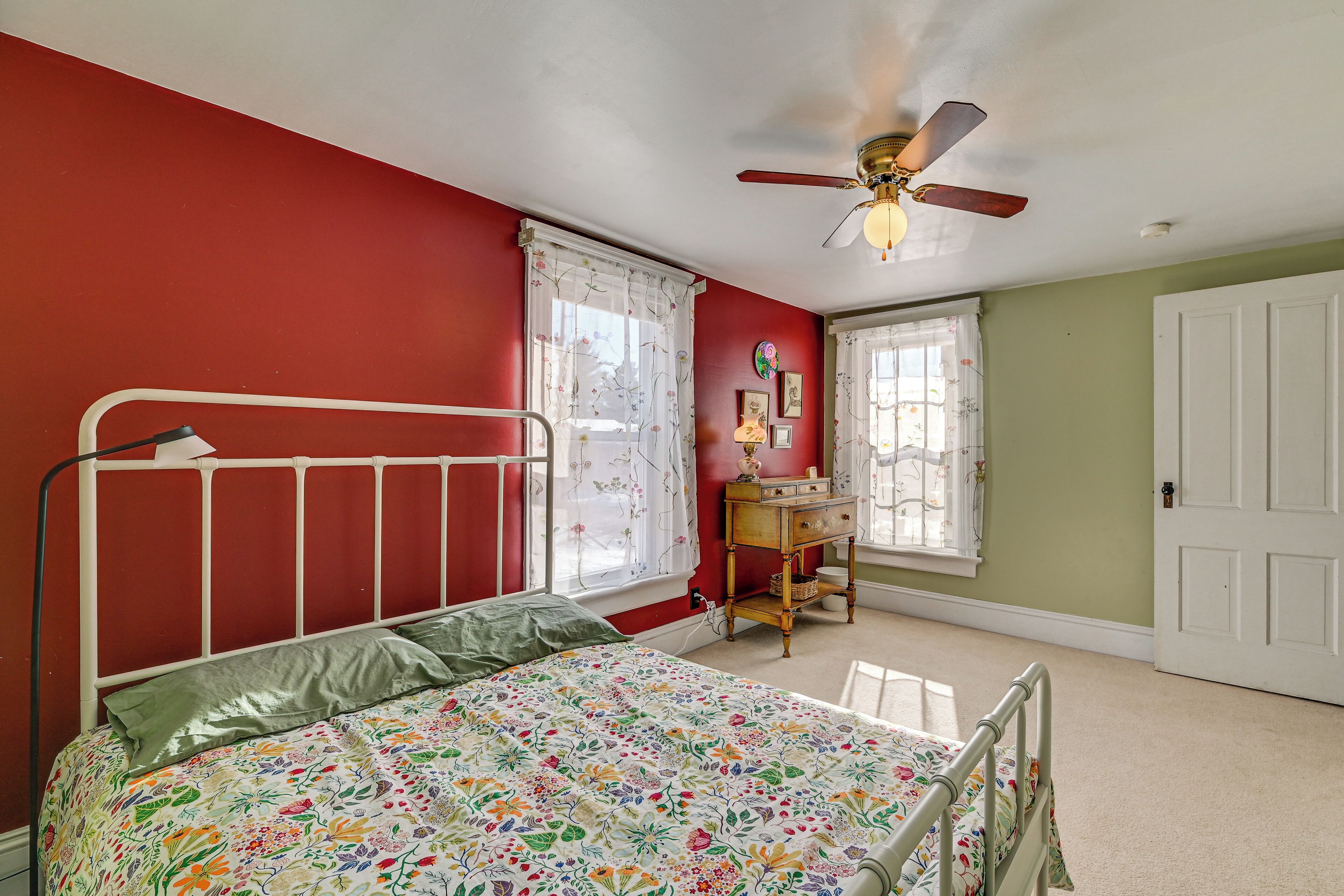 A bedroom with a bed, a dresser, a desk, and a ceiling fan.