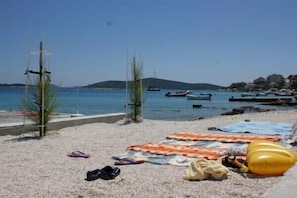 A beach with pebbles, a yellow inflatable, and boats in the water. - Three Bedroom Holiday Home (Sevid)