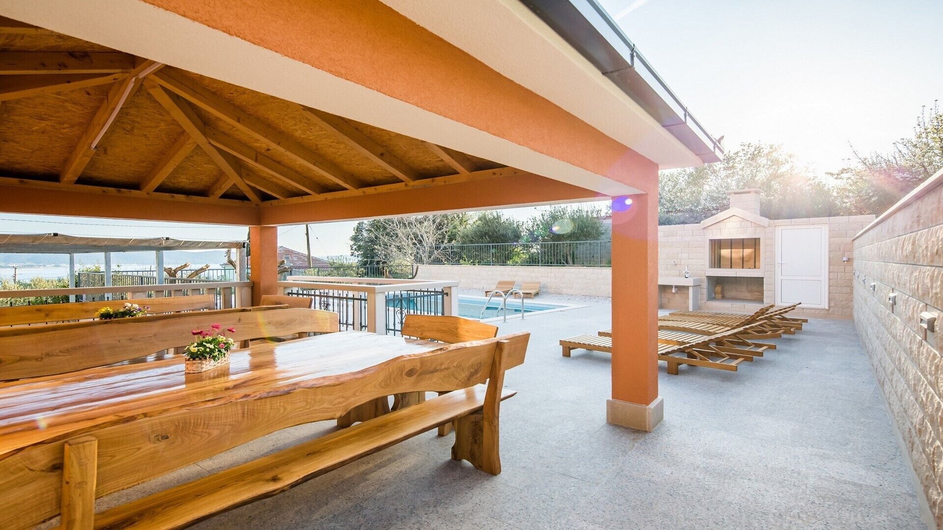 Eine Außenpatio mit Holzbanken und einem Poolbereich.