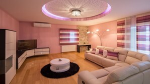 Una sala de estar moderna con televisor, sofá y una lámpara de techo original.
