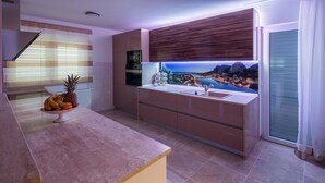 Una cocina moderna con una isla integrada, un amplio ventanal con vistas panorámicas y un frutero sobre la encimera.