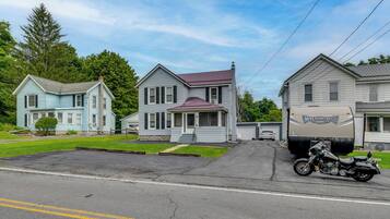 A residential street with two houses, a motorcycle, and a trailer.