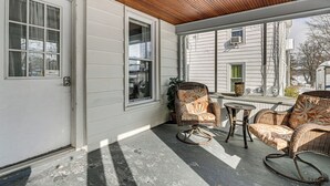 Ein überdachter Balkon mit Korbmöbeln, einem kleinen Tisch und Blick auf ein Nachbarhaus.