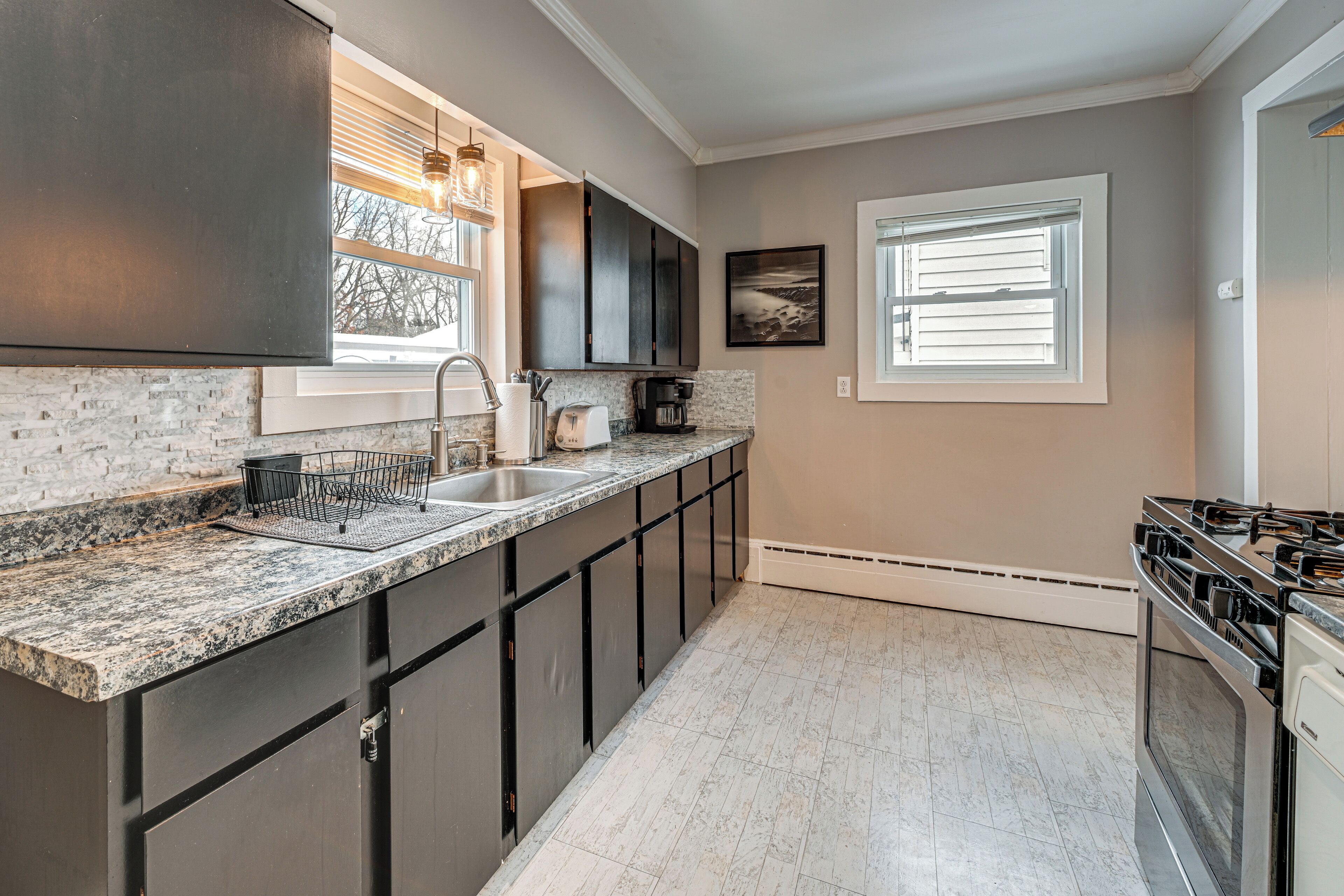 A modern kitchen with dark cabinets, granite countertops, a stainless steel sink, and a gas stove.