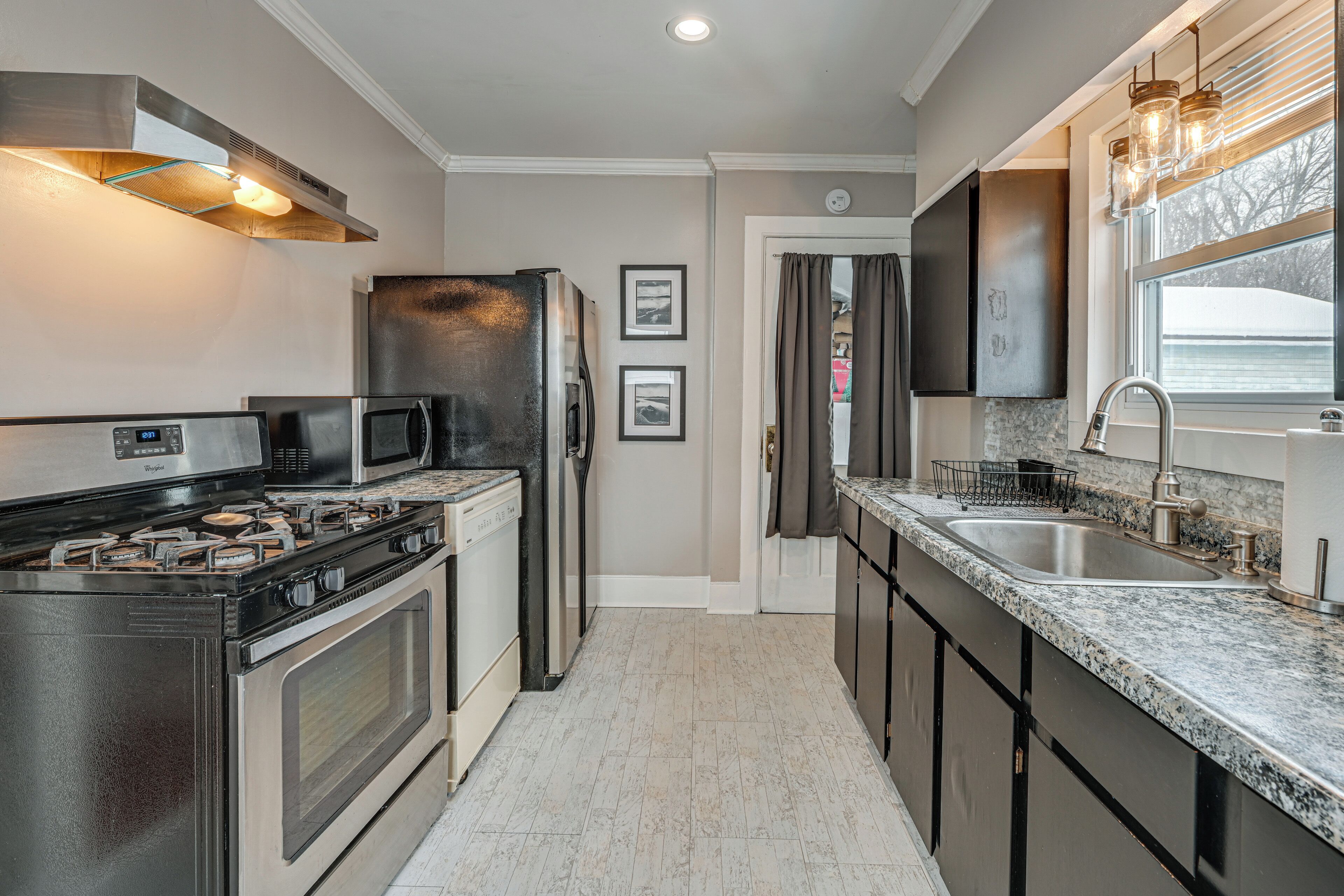 A modern kitchen with stainless steel appliances, a granite countertop, and a window with a view.