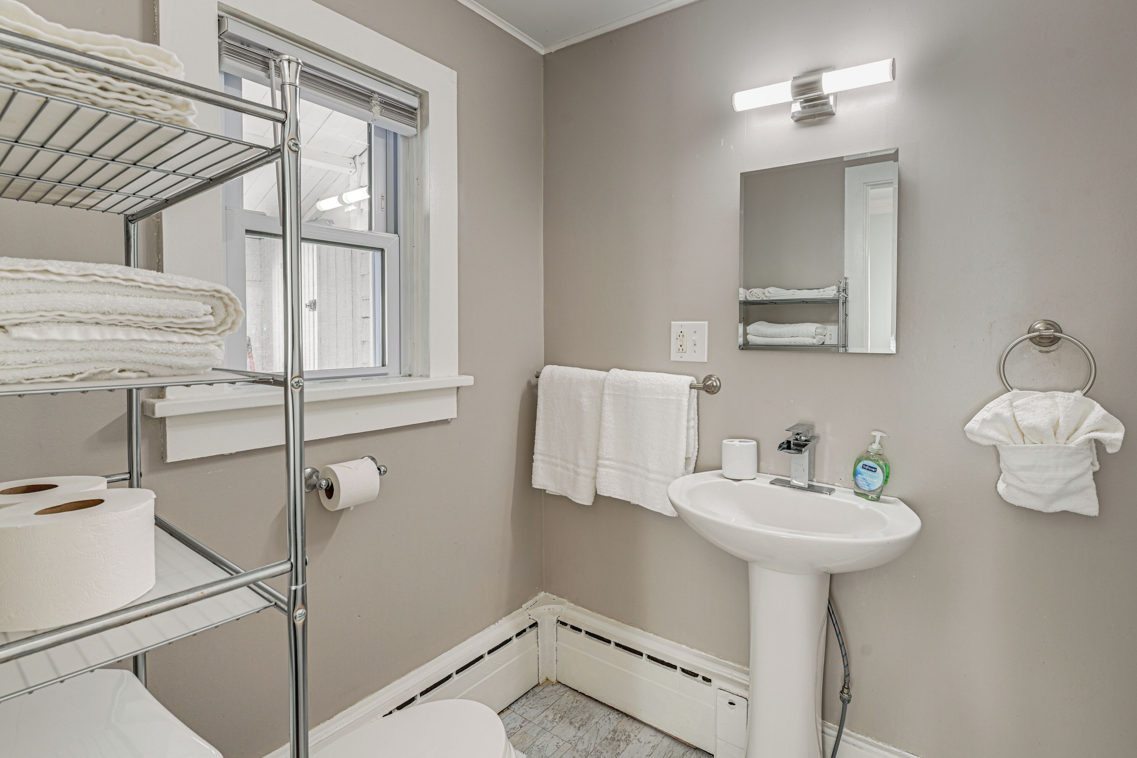 A compact bathroom with a white sink, a mirror, and a towel rack.