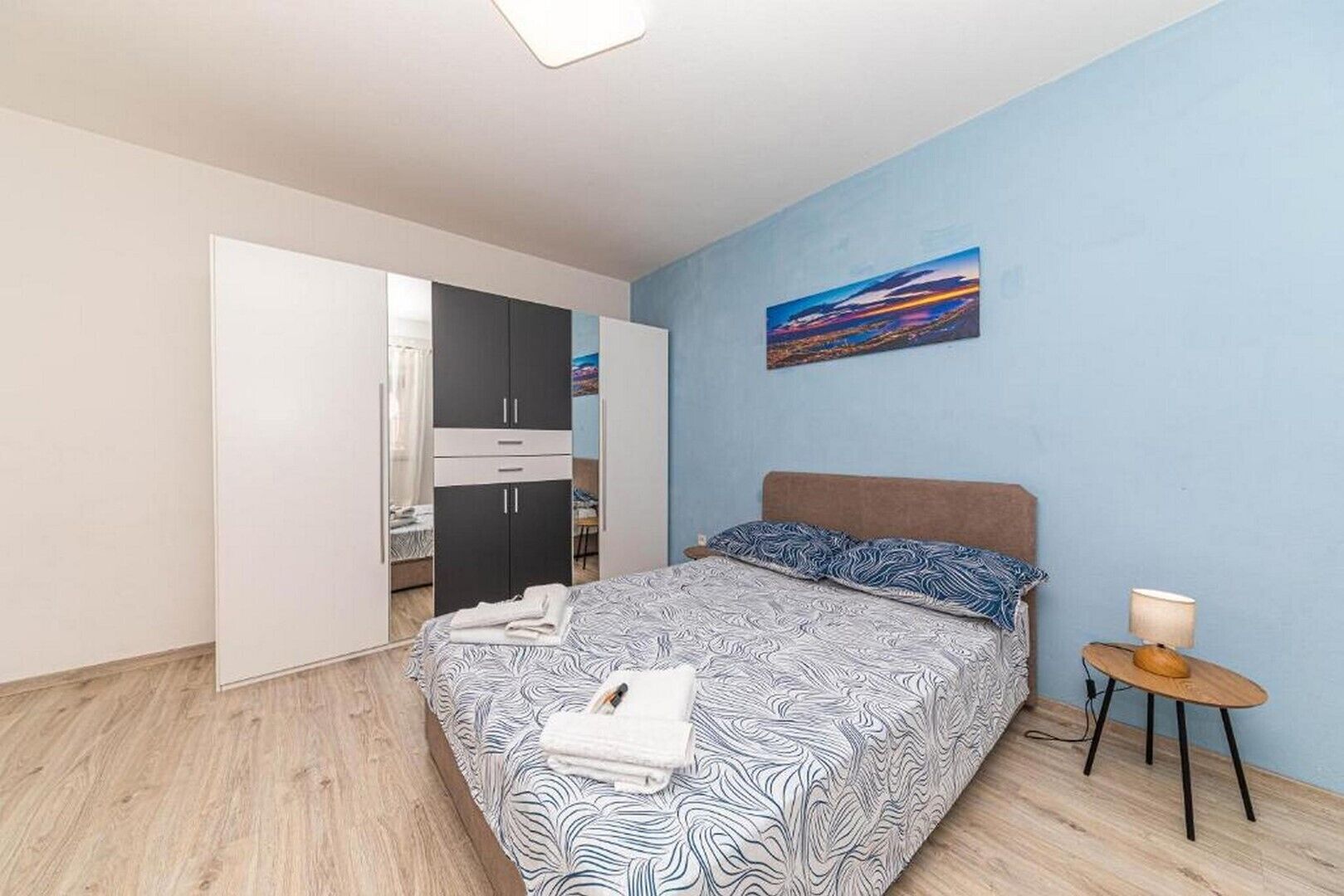 Une chambre à coucher avec un lit, une table de chevet, un tableau au mur et une armoire.