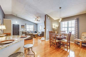 A spacious living area with a wooden floor, a dining table with chairs, a kitchen area with a marble countertop, and a ceiling fan. - Castlerea Casa Columbus Home w/ Deck & Yard (Columbus)