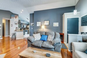 A modern living room with a grey sofa, wooden coffee table, and a kitchen in the background. - Castlerea Casa Columbus Home w/ Deck & Yard (Columbus)