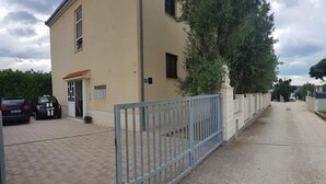 A building with a gated entrance, parked cars, and a paved driveway. - Two Bedroom Apartment (Kaštel Štafilić)