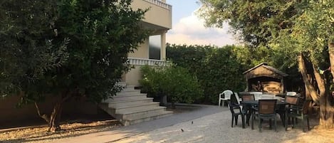 A building with a balcony, a gravel pathway, and outdoor seating.