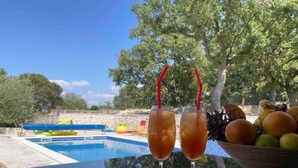 Ein Tisch am Pool mit zwei Gläsern Eistee und einer Obstschale.