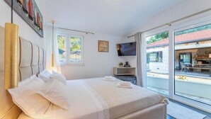 Ein Schlafzimmer mit einem Bett, einem Fernseher, einem Fenster und Blick ins Freie.