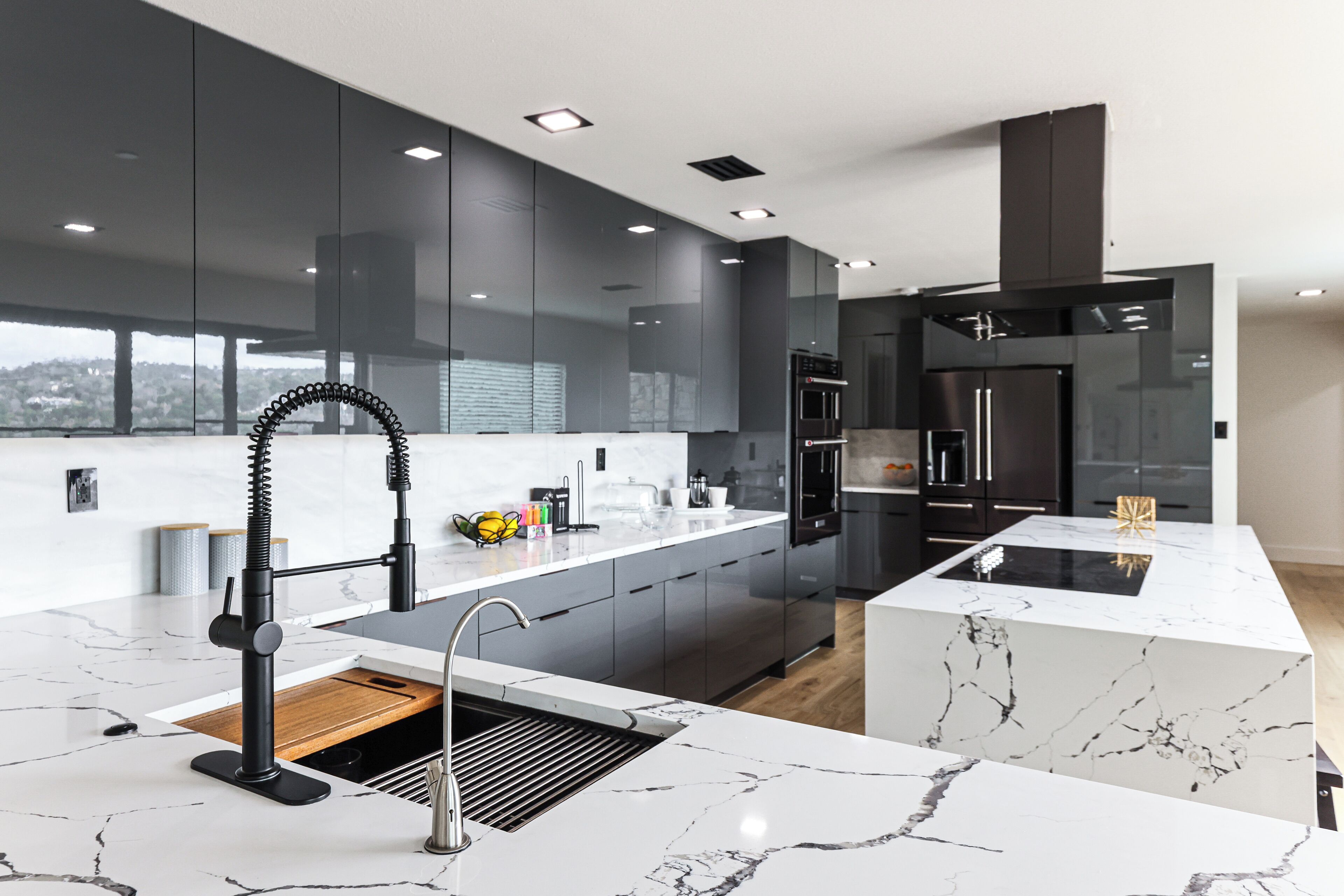 A modern kitchen with dark cabinetry, a marble countertop, and a built-in oven.