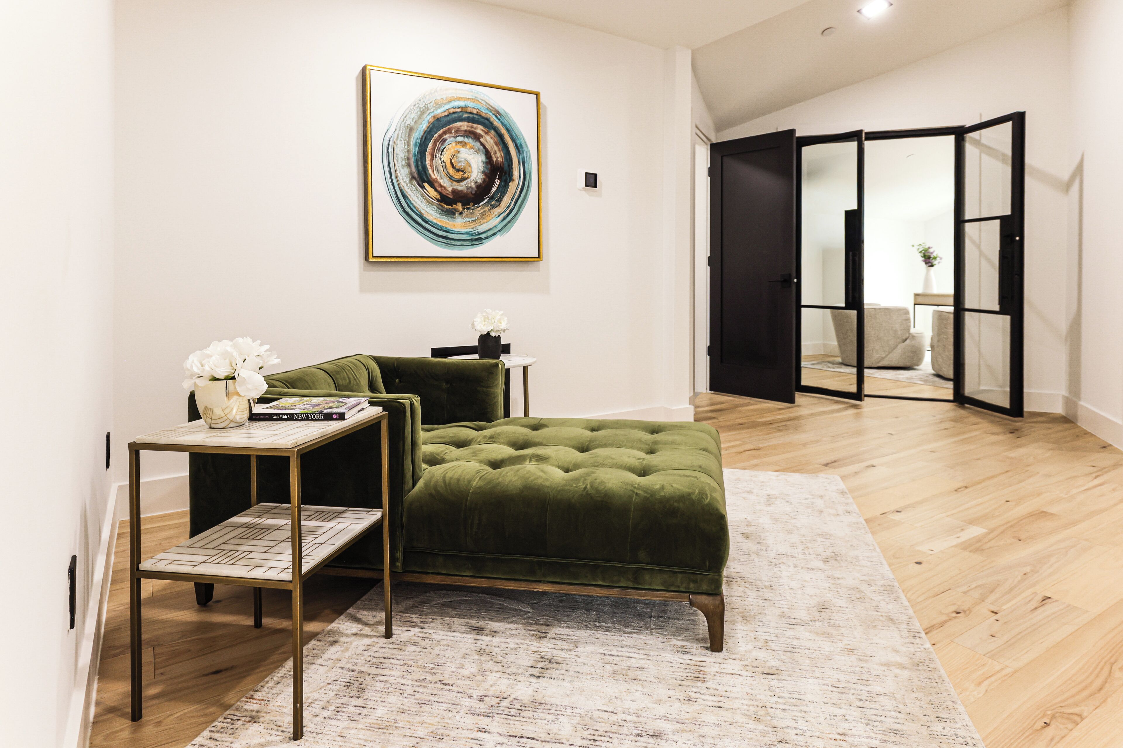 Un soggiorno moderno con un divano verde, un tavolino e un grande quadro astratto appeso al muro.