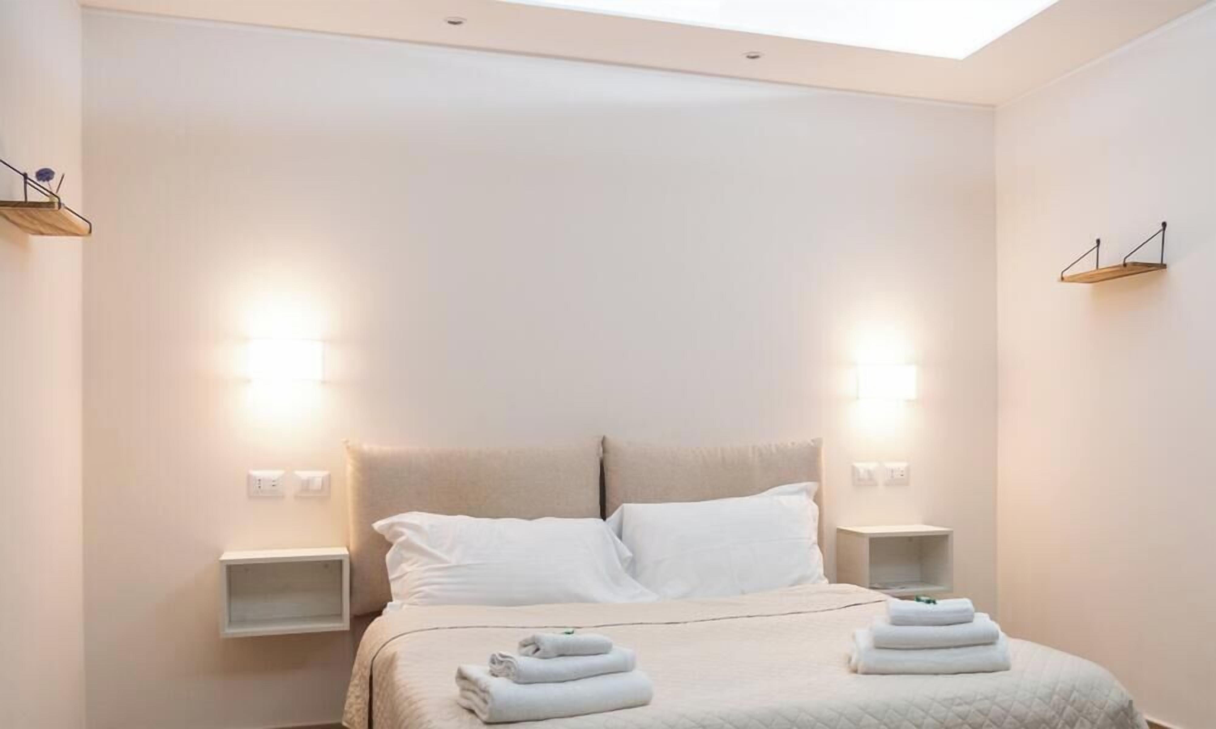 Una camera d'albergo moderna con un letto grande, due comodini e luci a parete.
