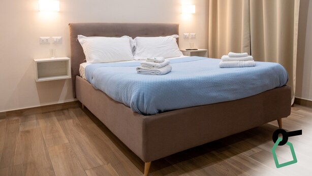 Een moderne hotelkamer met een groot bed, twee nachtkastjes en een raam met gordijnen.