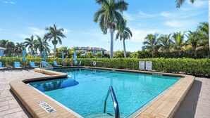 A swimming pool with lounge chairs and palm trees. - Harborside Terrace at Park Shore (Naples)