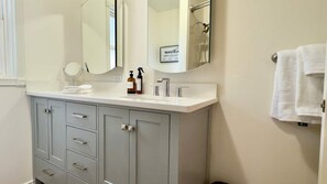 A bathroom with a white vanity, a mirror, and a towel hanging on the wall. - 3BR Lacey home with bonus room, workspace, fenced yard & patio near trail, shops, and I-5. (Lacey)