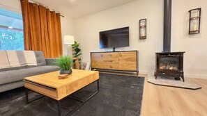 A modern living room with a sofa, coffee table, TV, and fireplace. - 3BR Lacey home with bonus room, workspace, fenced yard & patio near trail, shops, and I-5. (Lacey)