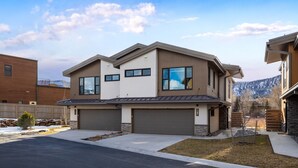 A modern two-story house with a garage, a well-maintained lawn, and a mountain backdrop. - New Listing! Peaceful Riverfront Living | Deck with Views | Walk to Downtown (Ridgway)