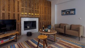Uma sala de estar com lareira, televisão, sofá e mesa de centro.