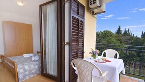 A balcony with a table set for two, a bed with a grey floral bedspread, and a wooden wardrobe. - Apartment With Pool Near Umag (Umag)